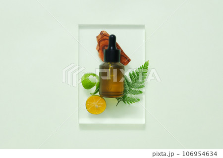 Top view of dropper bottle unbranded mockup decorated with kumquat slices on pastel green background. Scene for advertising cosmetic with natural ingredients 106954634