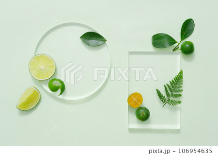 Against the pastel background, slices of lime and kumquat decorated with green leaves. Empty space on transparent podiums for display cosmetic product Against the pastel background, slices of lime and kumquat decorated with green leaves. Empty space on transparent podiums for display cosmetic product 106954635