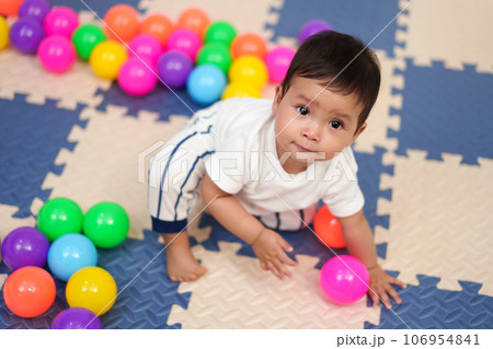 infant baby playing colorful balls in playpen 106954841