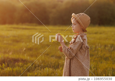 Little girl smelling flowers in a flower field Little girl smelling flowers in a flower field 106955030