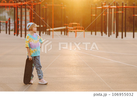 Fashionable child girl in casual clothes and jeans stands with skateboard 106955032