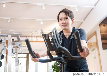 スポーツジムのエアロバイクで運動する男性（健康・ダイエット） 106955103