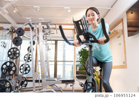 スポーツジムのエアロバイクで運動する女性（健康・ダイエット） 106955124