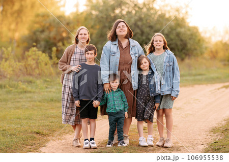 A large friendly family walks in a field in the summer A large friendly family walks in a field in the summer 106955538