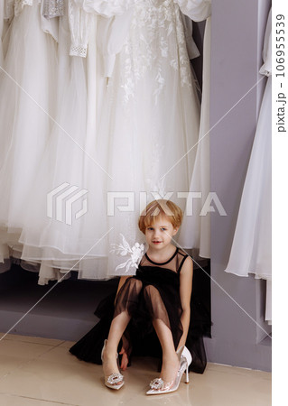 Little girl in a black evening dress in a clothing boutique 106955539