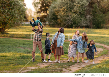 A large friendly family walks in a field in the summer 106955540