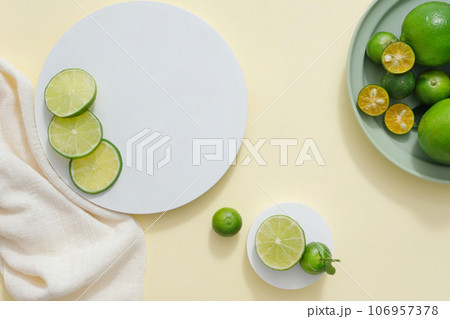 Light background featured podiums in round-shaped, white towel and a dish of kumquat and lime. Vacant space for beauty product advertising of Lime and Kumquat extract 106957378