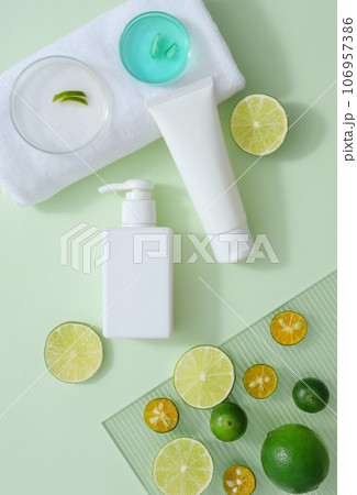 Petri dishes of blue liquid and peels put on white towel. Cosmetic containers decorated with kumquat and lime slices. Citrus fruits are known for their beneficial effects on the skin 106957386