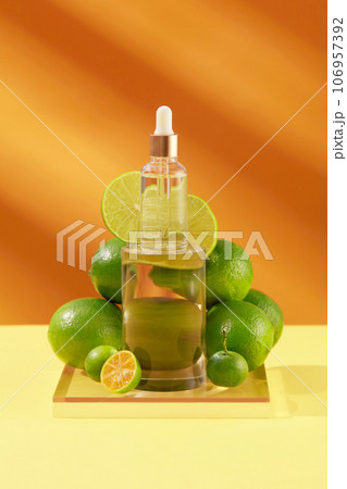 Unbranded dropper bottle standing on glass podium in cylinder-shaped with limes and kumquats surrounded. Empty label for cosmetic product mockup of Lime and Kumquat extract 106957392