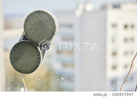 A window cleaner robot washes glass against the backdrop of multi-storey buildings. 106957847