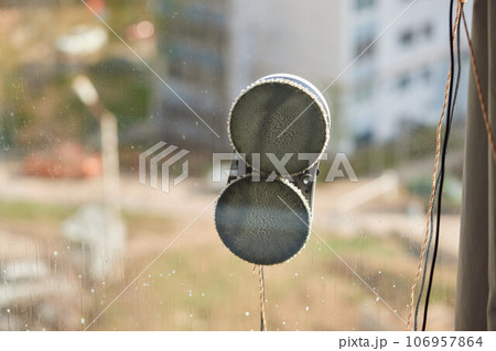 A window cleaner robot washes glass against the backdrop of multi-storey buildings. 106957864