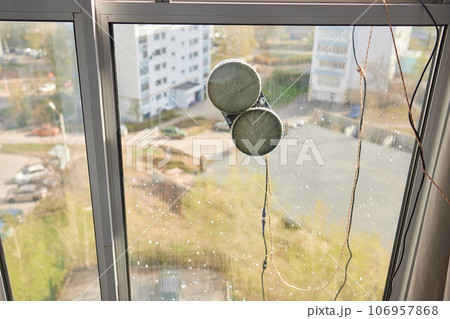 A window cleaner robot washes glass against the backdrop of multi-storey buildings. 106957868