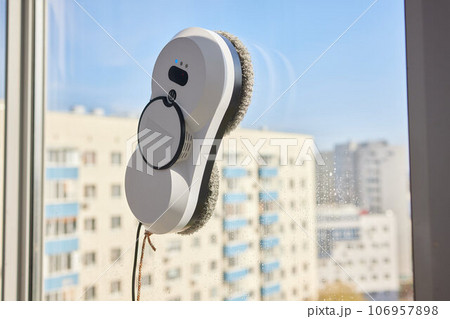 A window cleaner robot washes glass against the backdrop of multi-storey buildings. 106957898