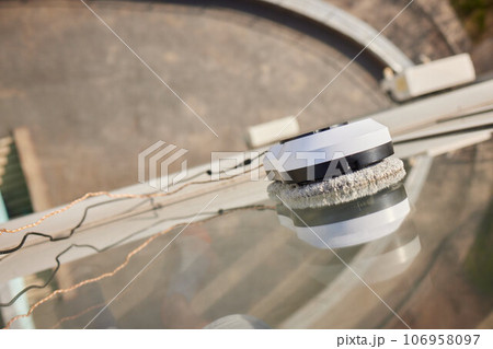A window cleaner robot washes glass against the backdrop of multi-storey buildings. 106958097
