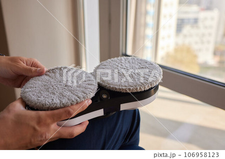A window cleaner robot washes glass against the backdrop of multi-storey buildings. 106958123