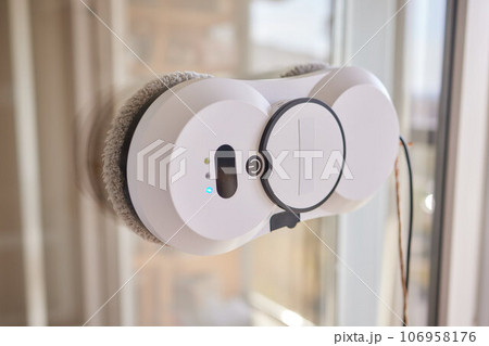 A window cleaner robot washes glass against the backdrop of multi-storey buildings. 106958176