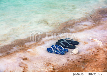 Beach scene Dead sea shore. Female and male flip flop sandals on the beach 106959270