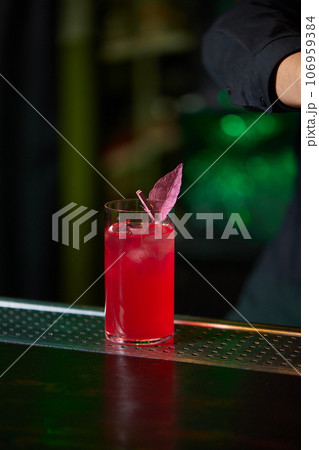 Barman in shirt and apron making an alcoholic drink with ice in a cocktail glass. Barman in shirt and apron making an alcoholic drink with ice in a cocktail glass. 106959384