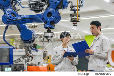製造機械の置かれた部屋で会話するエンジニア 106960565