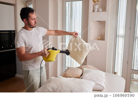 Using dry steam cleaner to sanitize pillow. 106960590