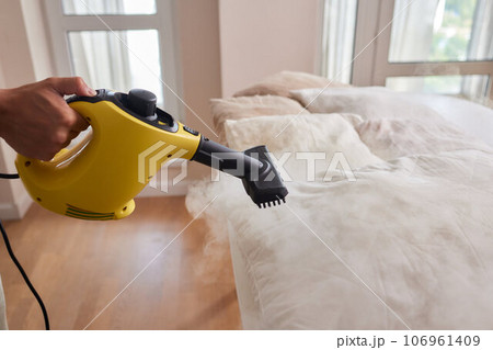 Using dry steam cleaner to sanitize pillow. 106961409
