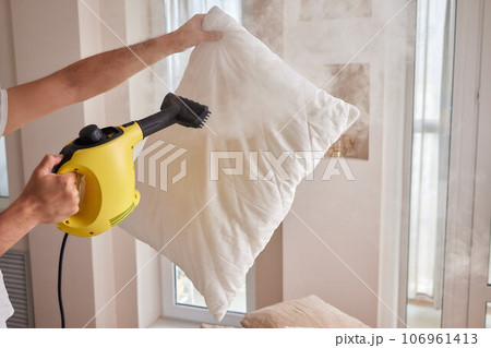 Using dry steam cleaner to sanitize pillow. 106961413