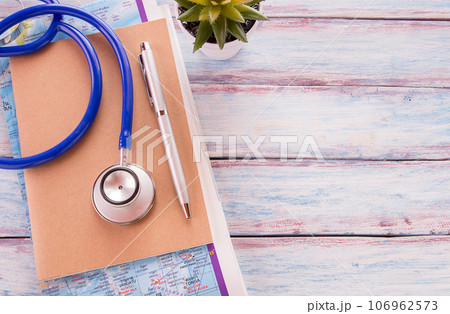 Flat lay photo with notebook, pen,map and blue stethoscope on wooden table background. 106962573