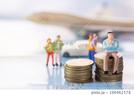 Businessman figures sitting on the coin with blurred car and airplane background. Businessman figures sitting on the coin with blurred car and airplane background. 106962578