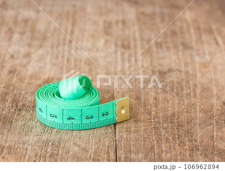 Close up green measuring tape on wooden table Close up green measuring tape on wooden table 106962894