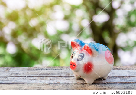 Piggy bank on wooden table over blurred background Piggy bank on wooden table over blurred background 106963189
