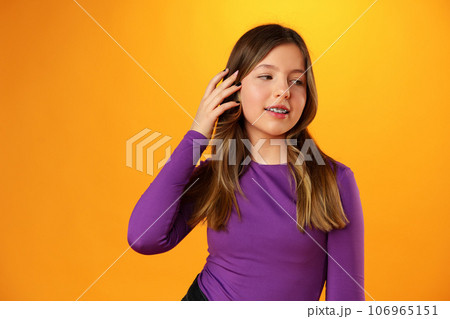 Photo of teen girl smiling portrait against yellow background in studio Photo of teen girl smiling portrait against yellow background in studio 106965151