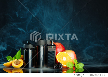 Vape and smoking liquid with fruit against black background with smoke Vape and smoking liquid with fruit against black background with smoke 106965155