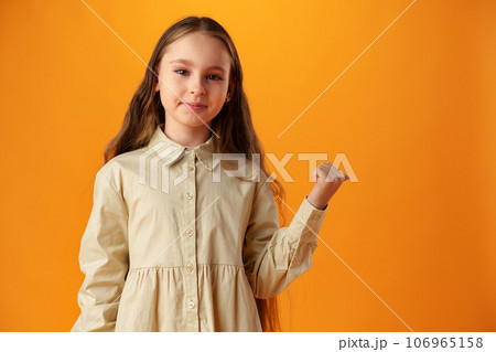 Teenager girl over yellow background pointing finger to copy space Teenager girl over yellow background pointing finger to copy space 106965158