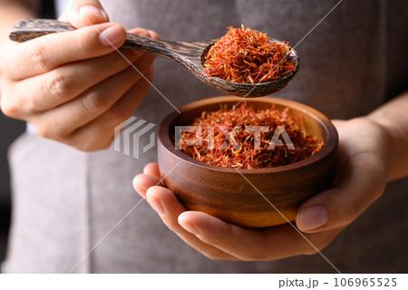 Dried safflower in wooden bowl and spoon holding by hand, Herbal tea 106965525