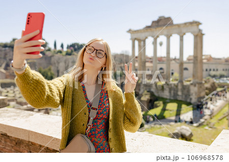 Young happy woman with peace sign takes selfie photo near the Roman Forum, old ruins at the center of Rome, Italy. Concept of traveling famous landmarks. Young happy woman with peace sign takes selfie photo near the Roman Forum, old ruins at the center of Rome, Italy. Concept of traveling famous landmarks. 106968578