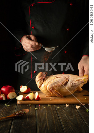 The cook adds paprika to raw duck before roasting in the oven. Cooking a national dish with apples in the restaurant kitchen by the hands of a chef 106968641