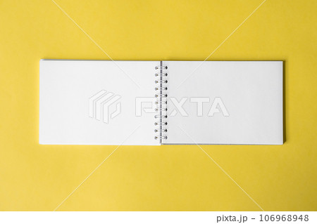 Opened notepad on a yellow background. Composition of writing to-dos for the day. The notebook lies on a plain background with space for writing.  106968948