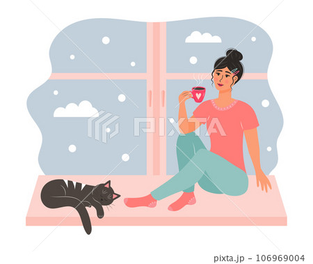 Young woman sitting on the window with a mug of hot drink and cute cat sleeping near her. Snowy day weather outside the window. 106969004