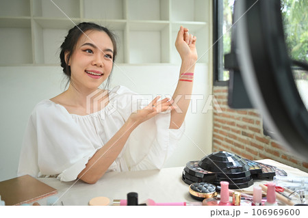 Confident female blogger testing new lipstick different color on her hand recording make up tutorial at home Confident female blogger testing new lipstick different color on her hand recording make up tutorial at home 106969600
