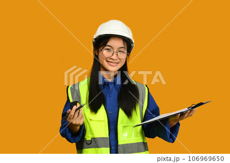 Future dream job career as engineer and architect. Smiling Asian girl holding helmet isolated on yellow background Future dream job career as engineer and architect. Smiling Asian girl holding helmet isolated on yellow background 106969650