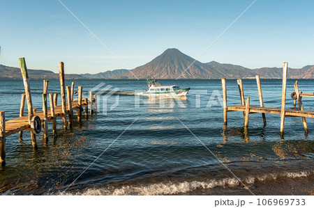 Wooden docks on Lake Atitlan on the beach in Panajachel, Guatemala. With Toliman and San Pedro volcanoes in the background 106969733
