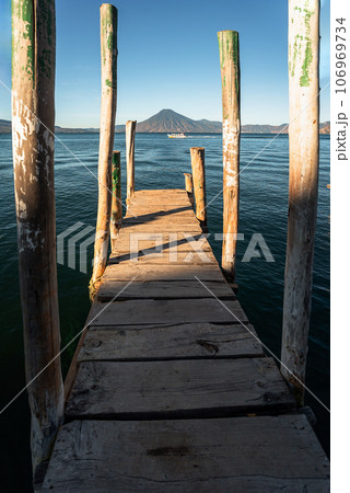 Wooden dock on Lake Atitlan on the beach in Panajachel, Guatemala. With Toliman and San Pedro volcanoes in the background 106969734