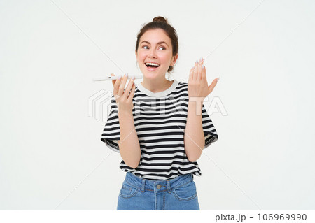 Image of chatty, happy young woman talking on mobile phone, recording voice message, explaining something over the telephone, white background 106969990