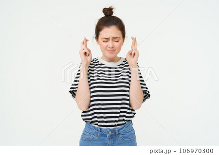 Portrait of hopeful young woman, makes wish, cross fingers for good luck, wishing, anticipating, standing over white background Portrait of hopeful young woman, makes wish, cross fingers for good luck, wishing, anticipating, standing over white background 106970300