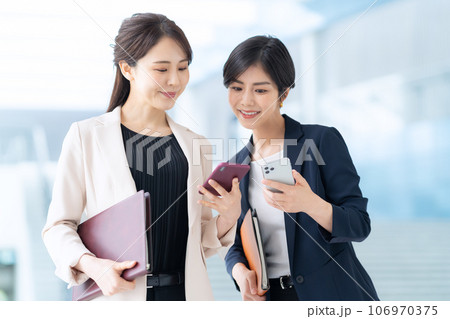 オフィスでスマホを使って打ち合わせをする若いビジネスウーマン 106970375