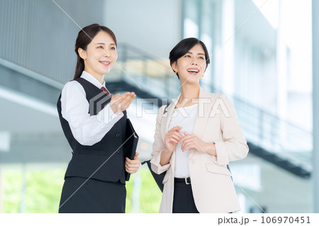 オフィスのロビーで若いビジネスウーマンを案内する受付嬢 オフィスのロビーで若いビジネスウーマンを案内する受付嬢 106970451