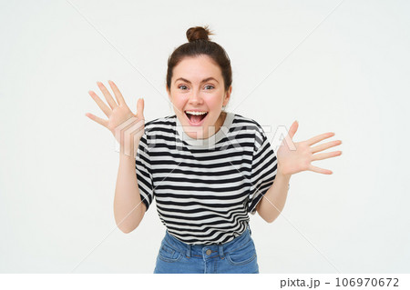 Portrait of happy, beautiful girl makes jazz hands, tells big news, revelation, introduces surprise, stands over white background 106970672