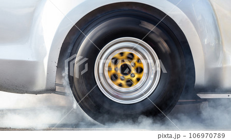 Close up car wheel with smoke on the asphalt road speed track, Car wheel drifting and smoking on track, Car wheel spinning. 106970789