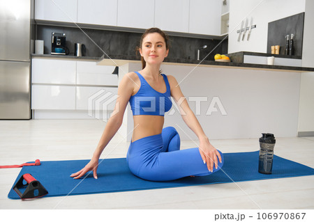 Image of woman does yoga practices from home, sits on rubber mat and meditating, workout in living room, concentrating on breathing exercises 106970867
