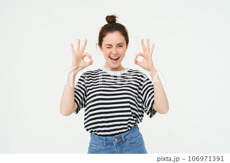 Excellent choice. Smiling stylish young woman, showing okay, ok gesture, zero sign, standing over white background Excellent choice. Smiling stylish young woman, showing okay, ok gesture, zero sign, standing over white background 106971391